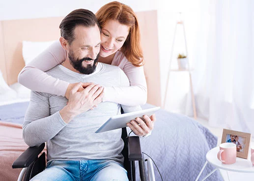 woman hugging man while he looks at tablet