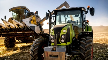 Combine harvester and tractor with trailer unloading harvest. Farmer details