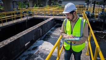 Engineer take water from wastewater treatment pond to check the quality of the water. After going through the wastewater treatment process