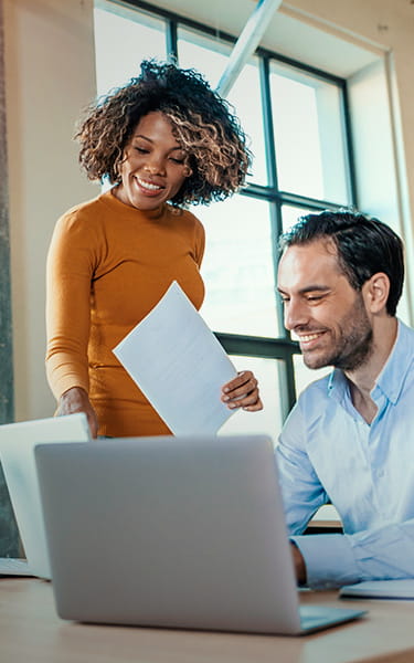 man and woman smiling at computer