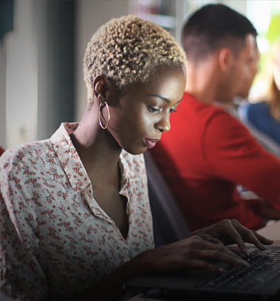 Woman in office types on her laptop keyboard