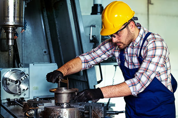 worker with safety helmet on his head, working with machines in workshop