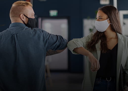 Elbow bump between two masked workers