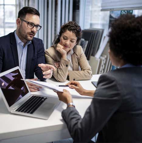 Business Colleagues Talking While Using Laptop At Office