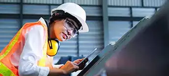 woman in hard hat sanding something metallic