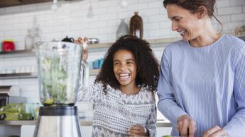 young girl making healthy smoothie happily