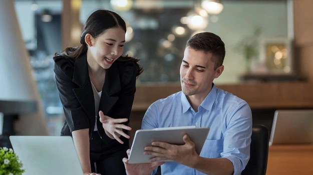 male and female colleague discussing business over a tablet