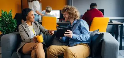 two colleagues happily sitting together in work space