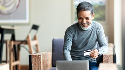 man holding credit card while working on laptop