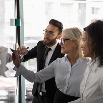 group of colleagues working together at whiteboard