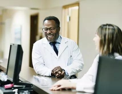 Laughing doctor in discussion with colleagues in hospital