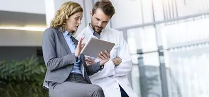 Businesswoman with tablet and doctor talking in hospital