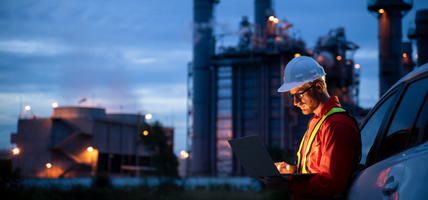 man in hard hat working on laptop at dusk