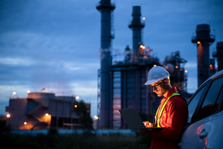 man in hard hat working on laptop at dusk