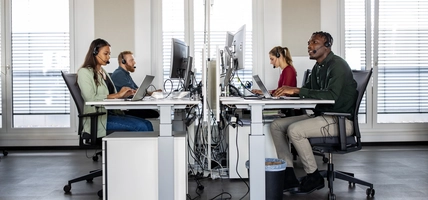 Group of help desk operators wearing headsets and working at their computers in a call center