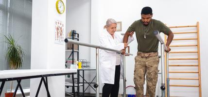 A female doctor assisting a man in walking