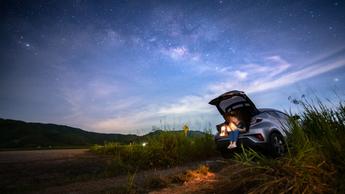 woman sitting in trunk of car with dusk sky above