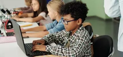 Side view of schoolboy working in front of laptop