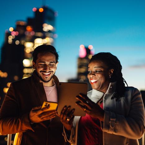 man and woman happily looking at tablet and mobile device together