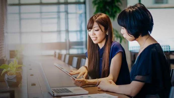 two women working together at a counter with laptop