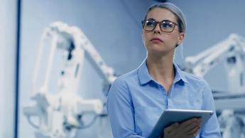 woman holding tablet among robotics