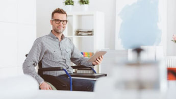 man in wheelchair happily sitting in office