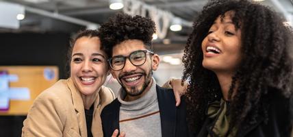 group of three smiling together in office setting