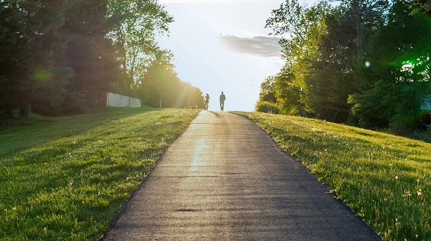 family walking dog on sidewalk