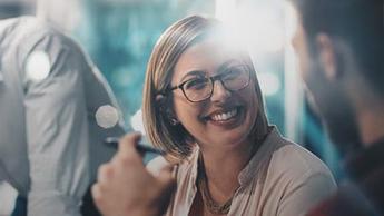 A female professional smiling and in discussion with her male colleague