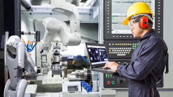 man working on laptop near machinery 