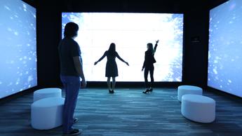 people standing in innovation studio against large screen