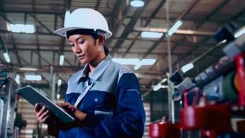 Engineer is using a tablet to check the machine's control system in a factory